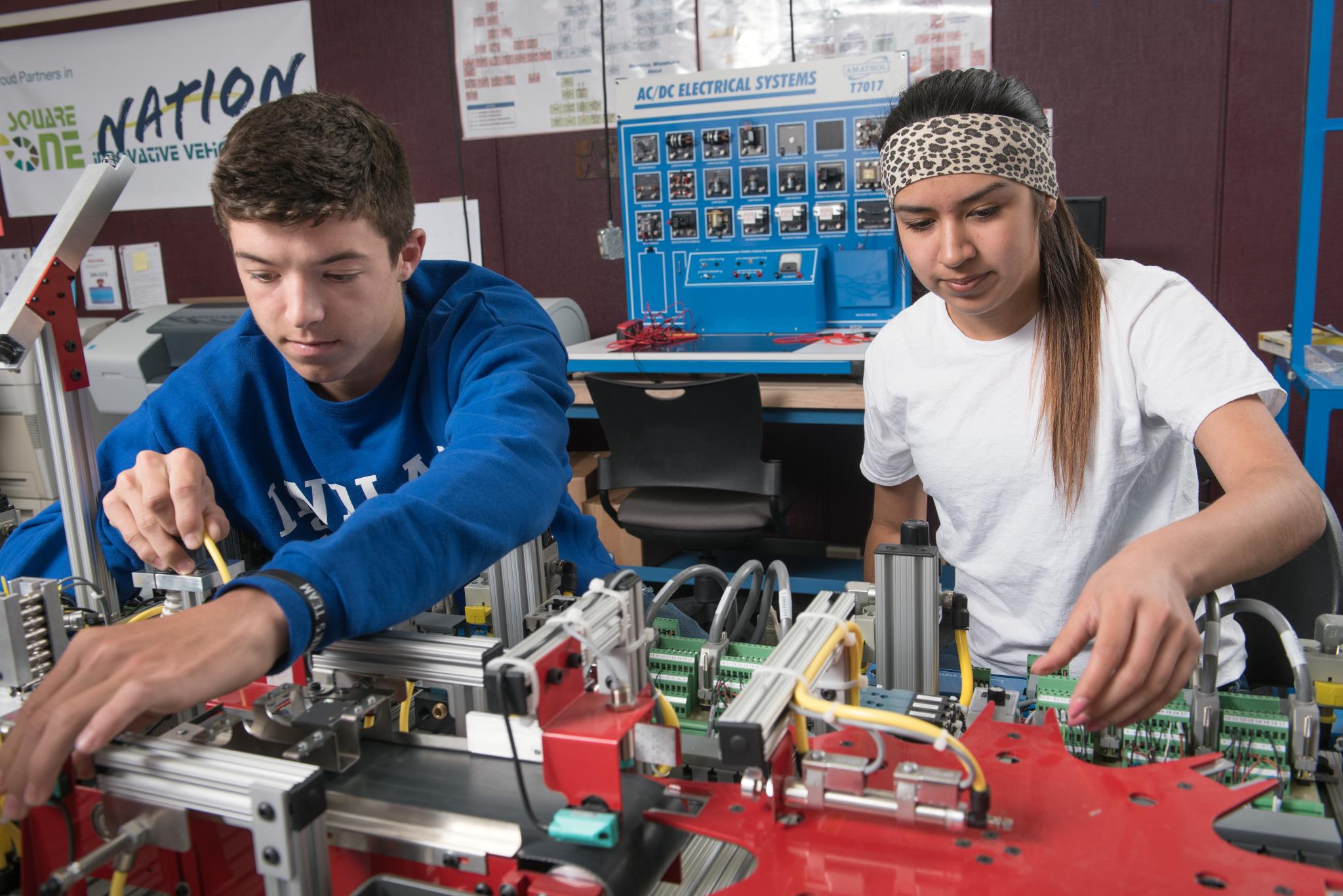 Two engineering students work on an automated process in class