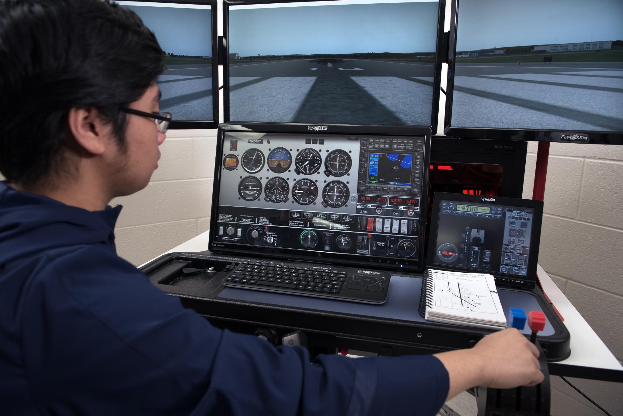 Aviation student simulates a flight on simulator equipment in the classroom.