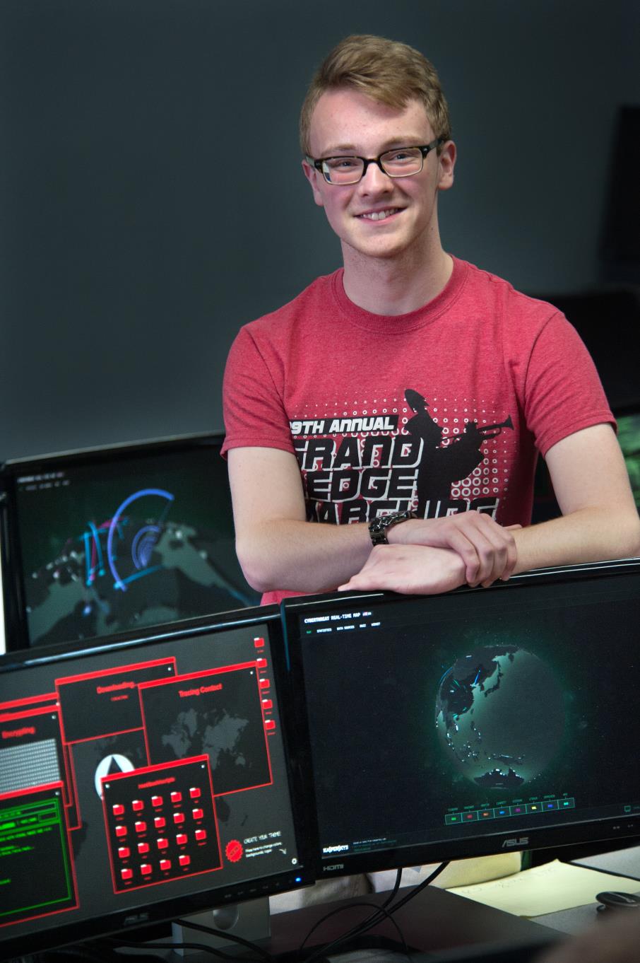 Male Cybersecurity student stands in front of his computer