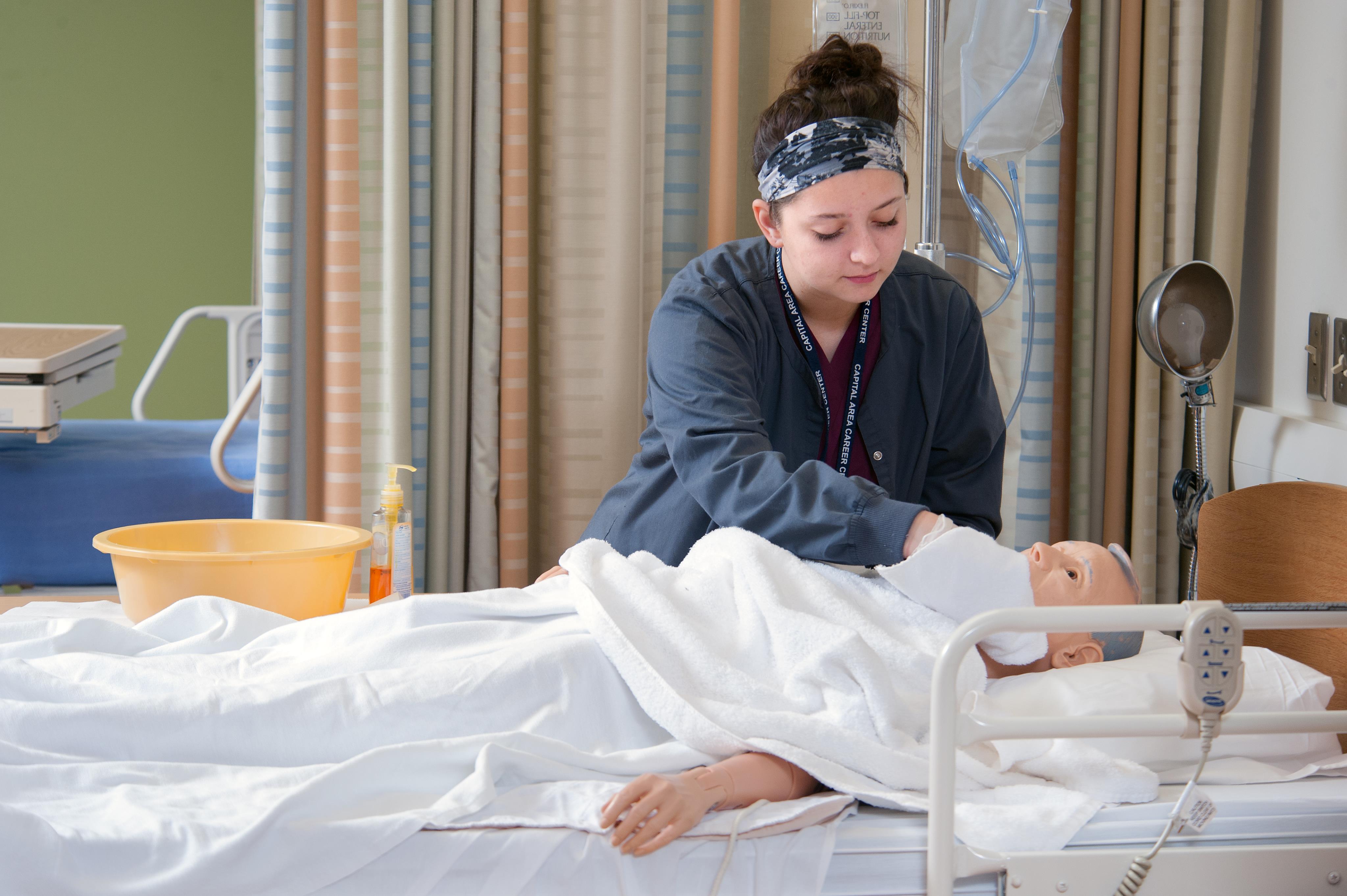 CNA student works on a patient in a hospital bed