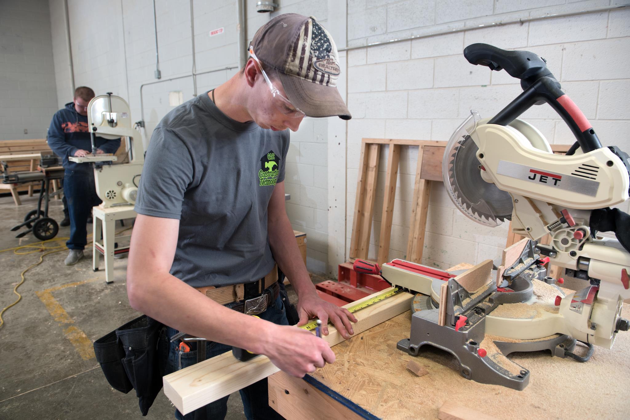 Male Construction student uses a saw to cut a piece of wood