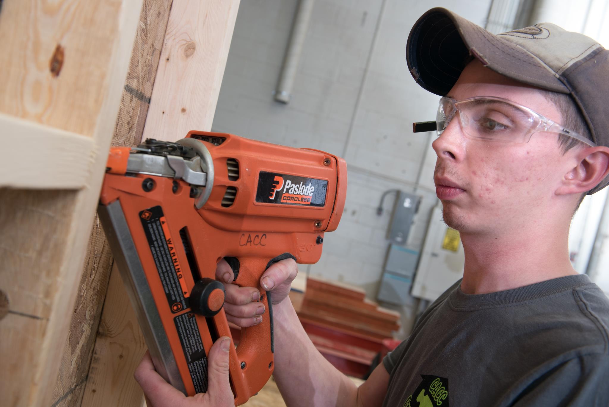 Male construction student uses a finish nailer on a piece of wood