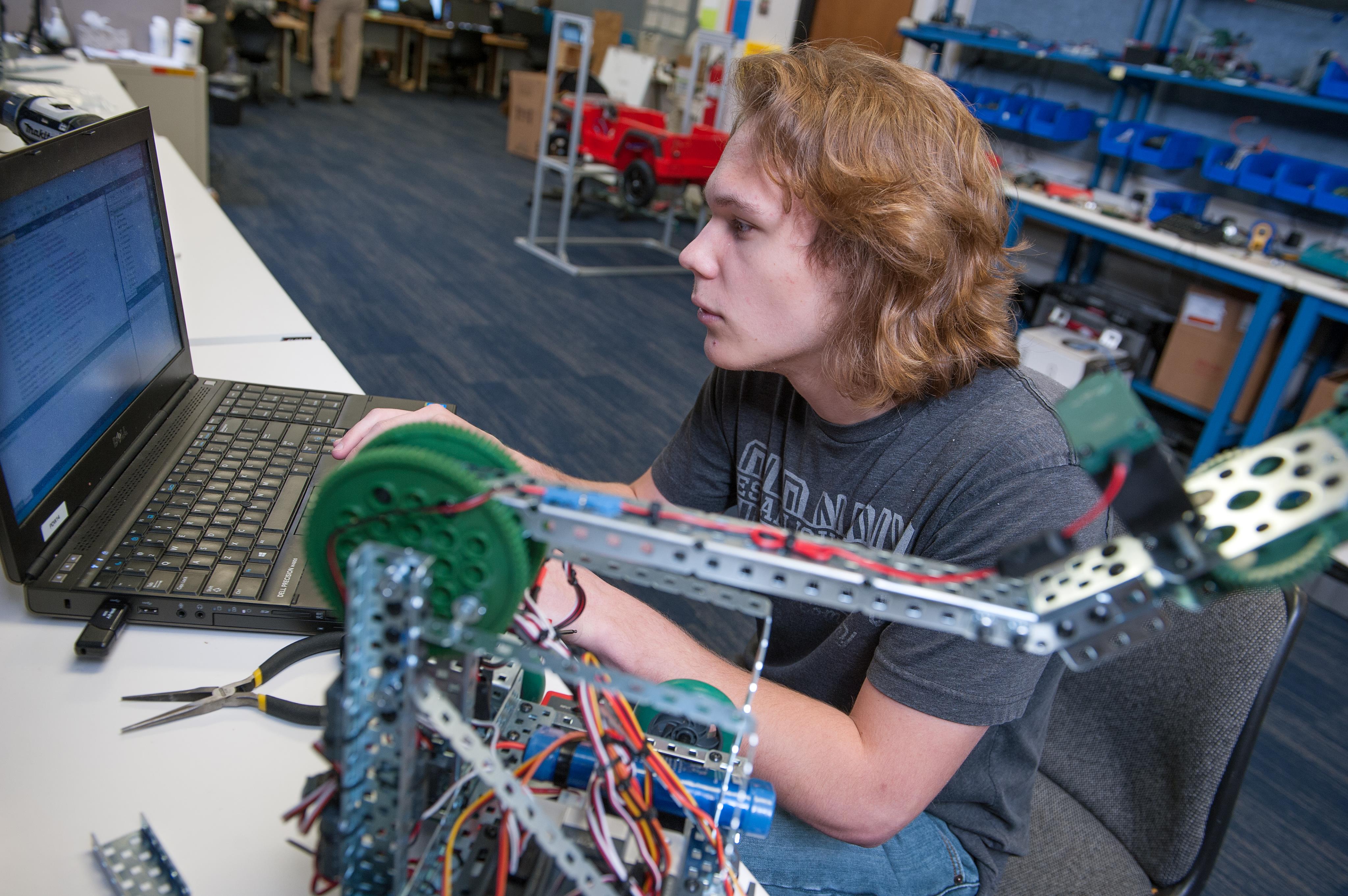 Male student in the Programming class works on programming some automation equipment