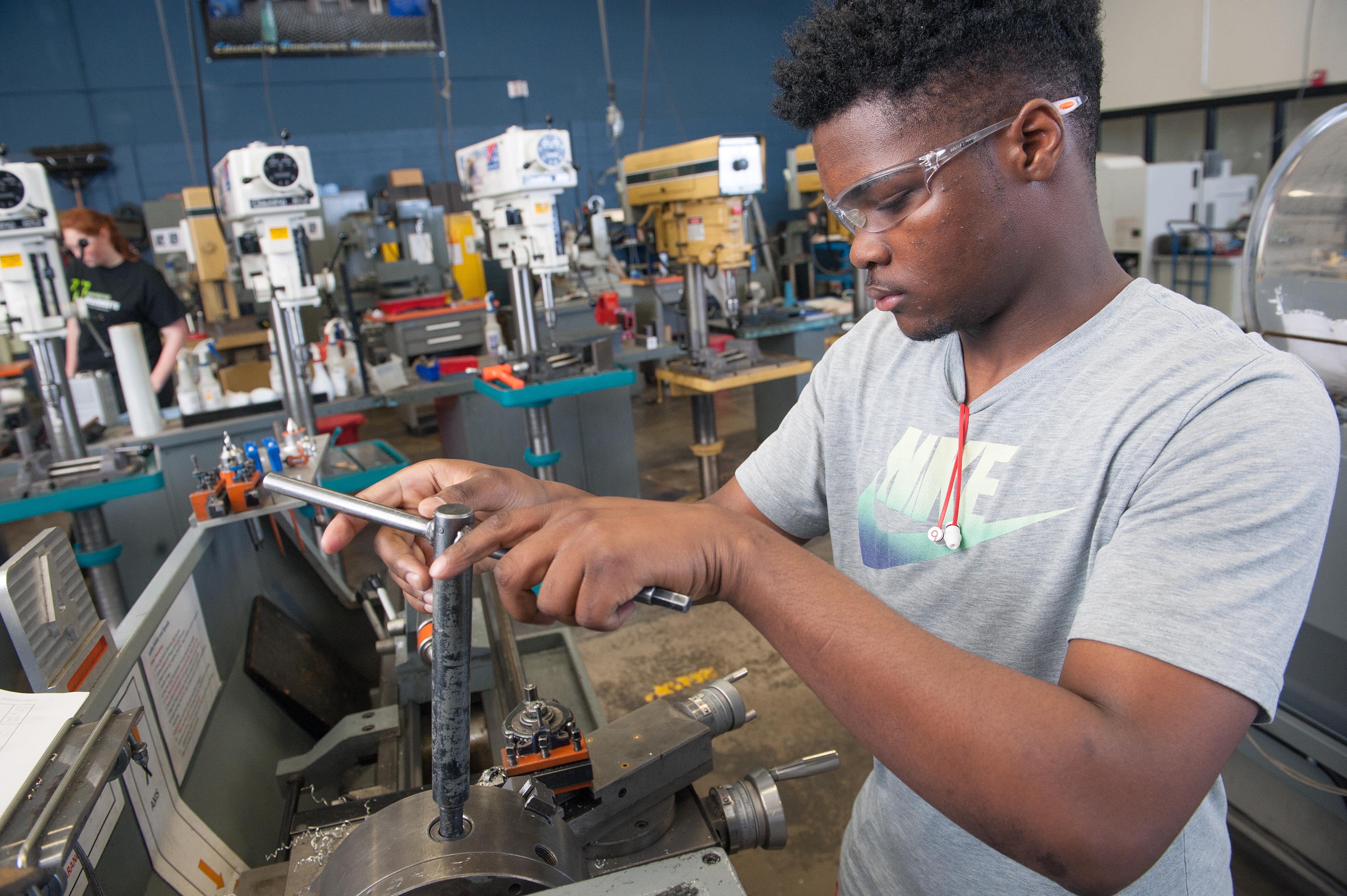 Male Precision Machining student working on a lathe in class