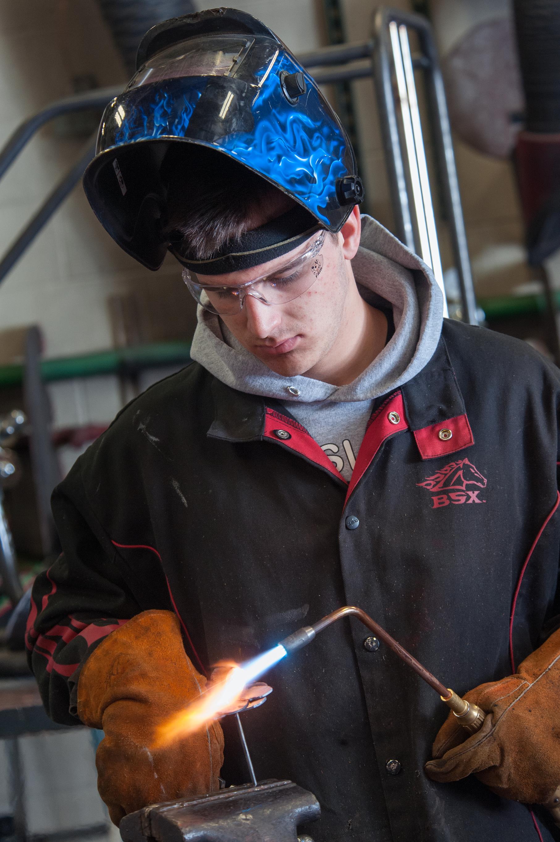 Male student in the welding program holds a welding torch