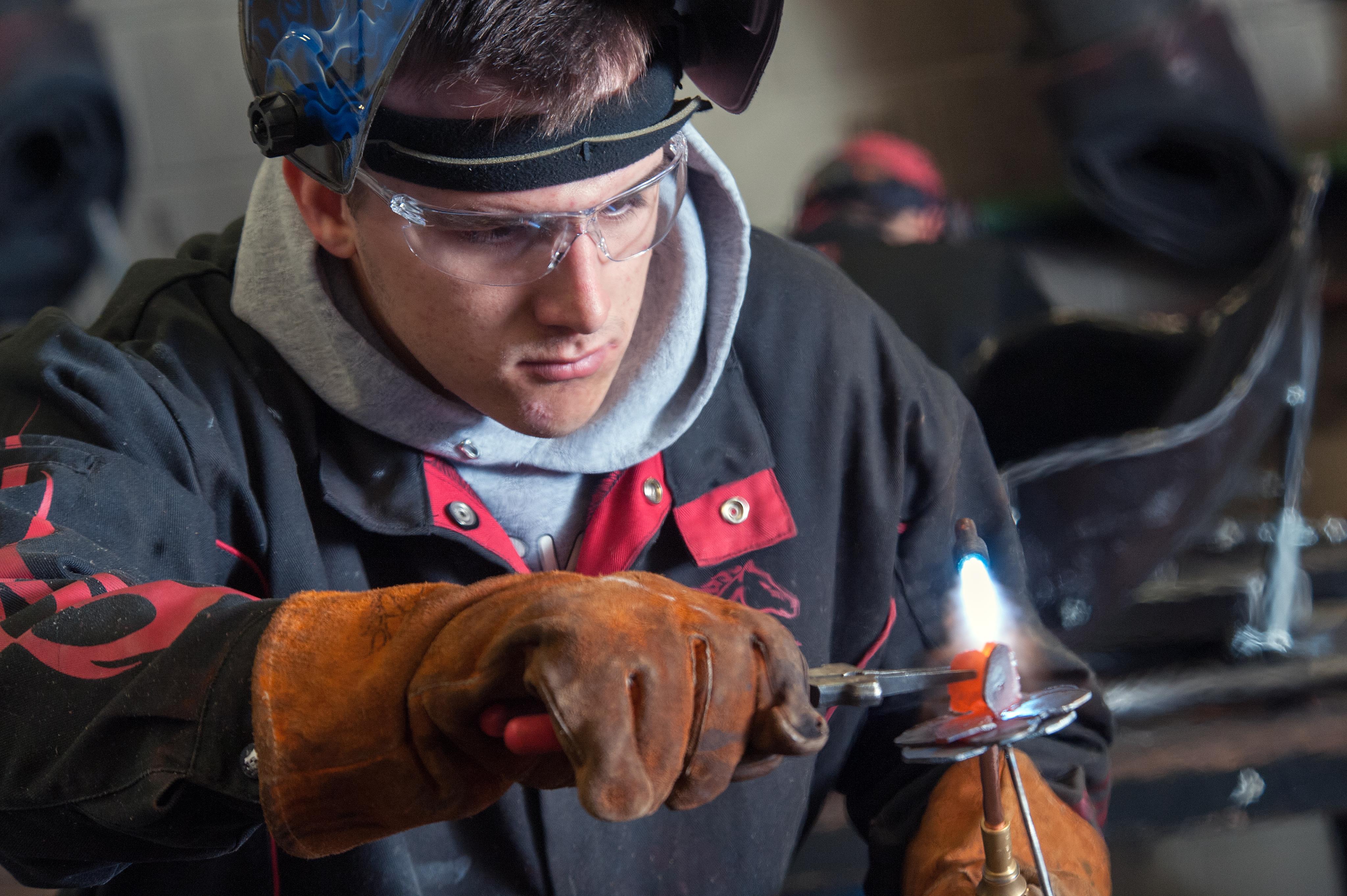Male student using a torch in the welding lab