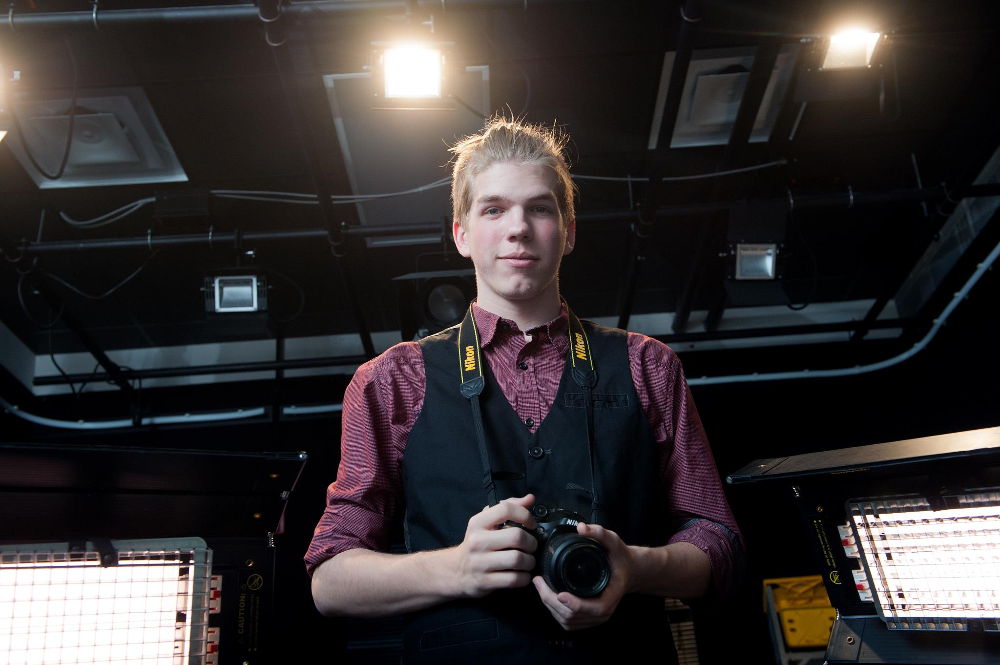 Male New Media student holding his camera in the photography studio