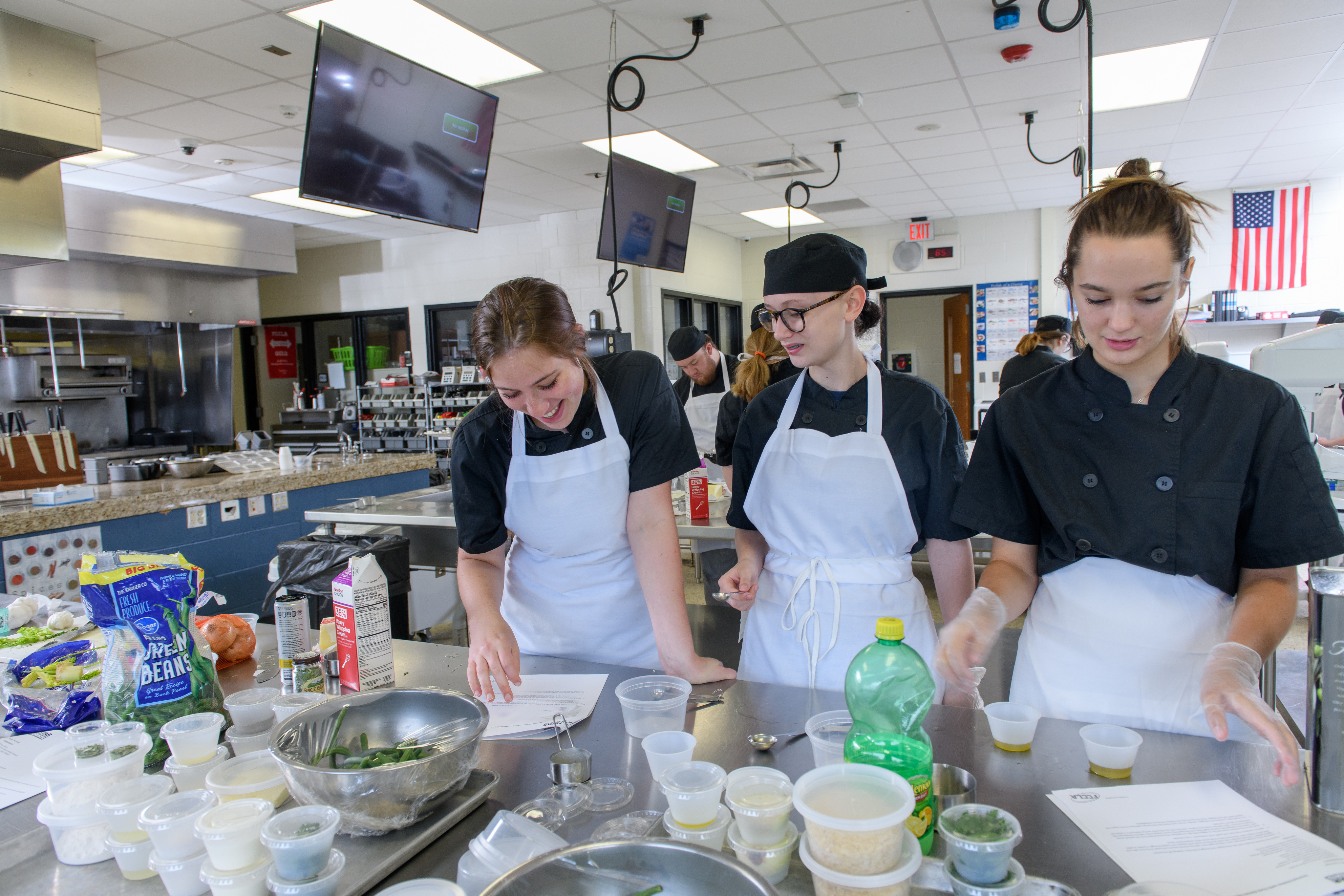 Three Culinary students work together in the lab on a recipe.