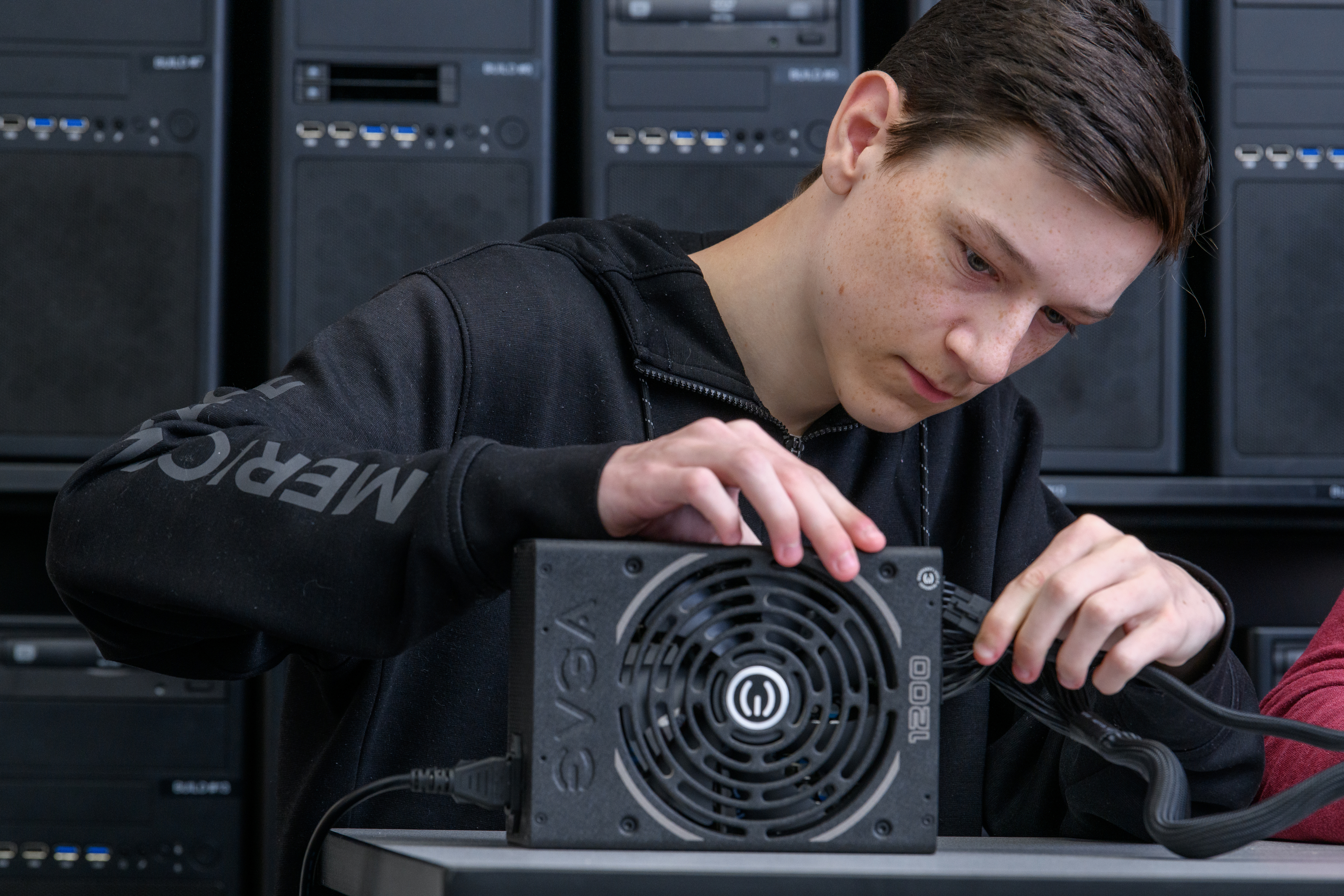 Male Cybersecurity student works on equipment for a computer in the lab.