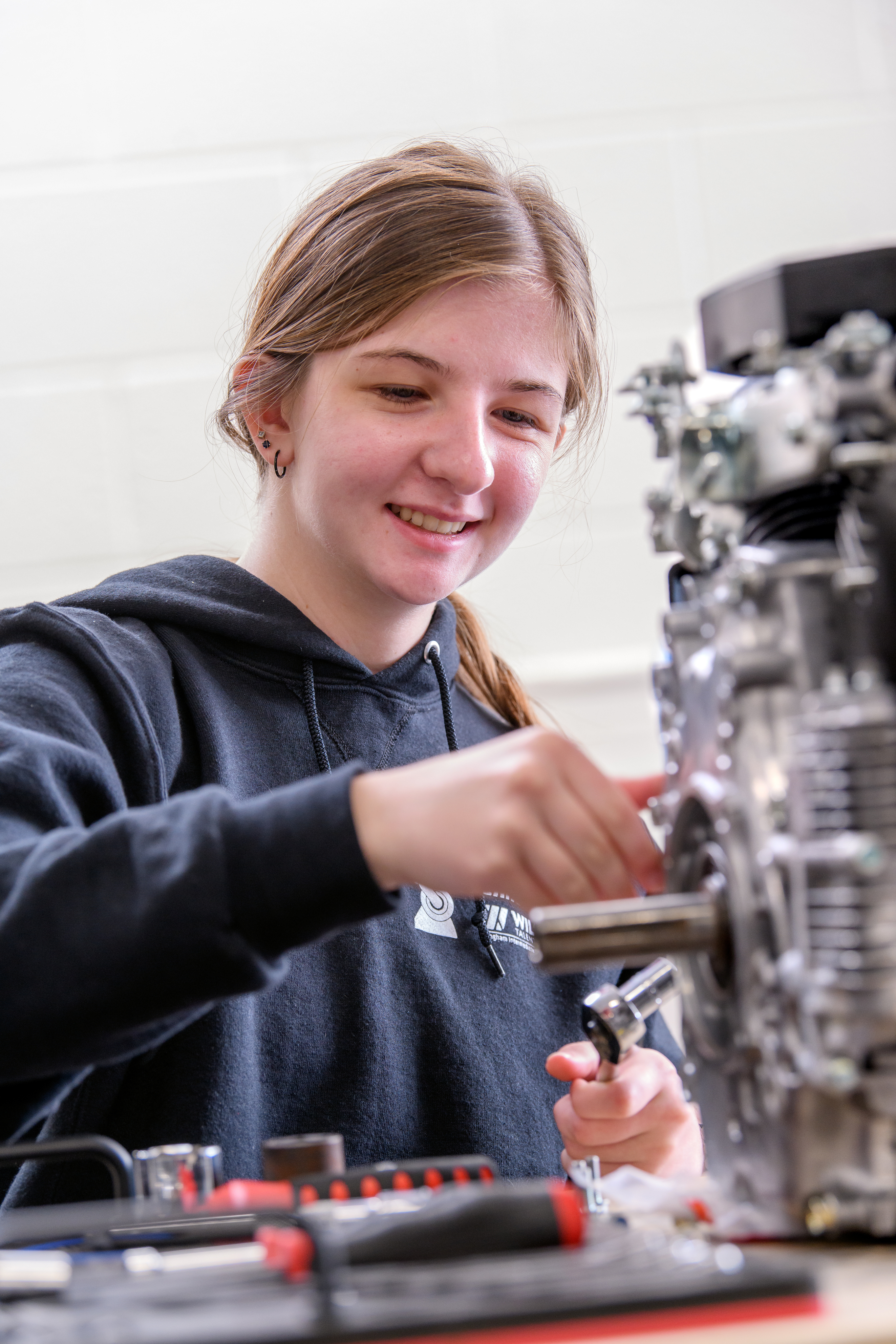 Engineering student works on the motor of a car in the lab.