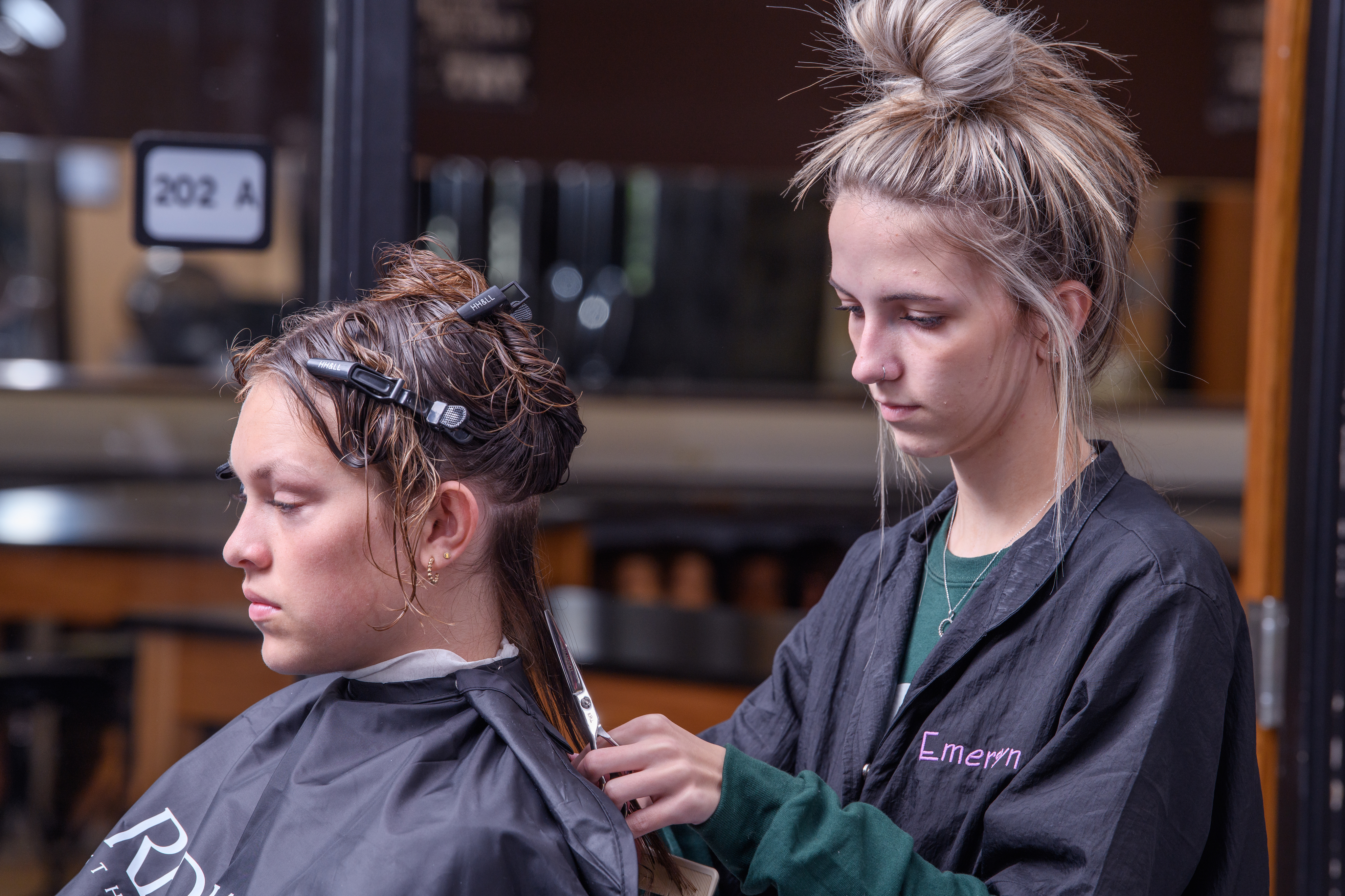 Female cosmetology student begins a haircut on a guest in the salon.