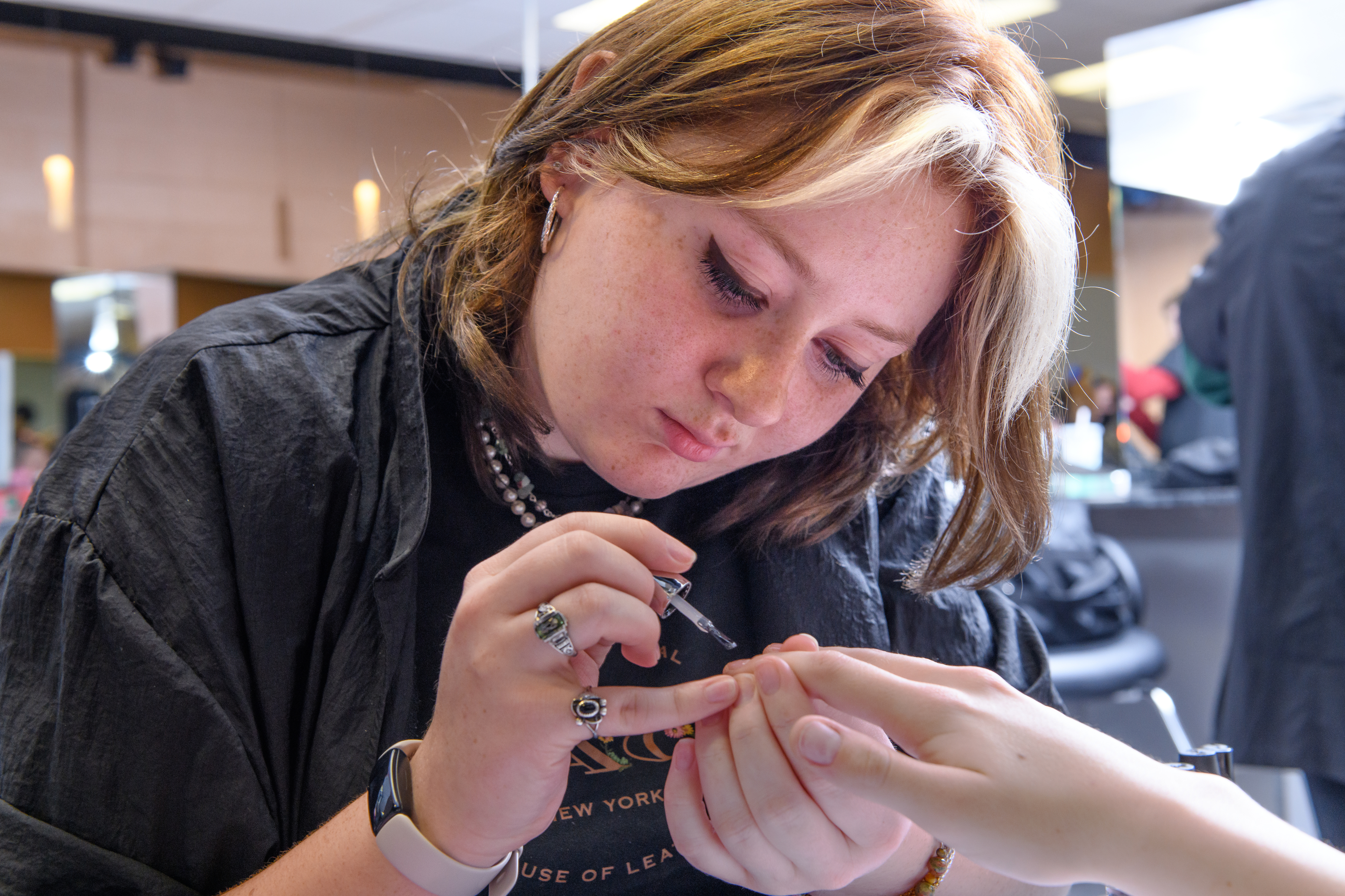 Manicuring student paints the nails of a customer in the salon.