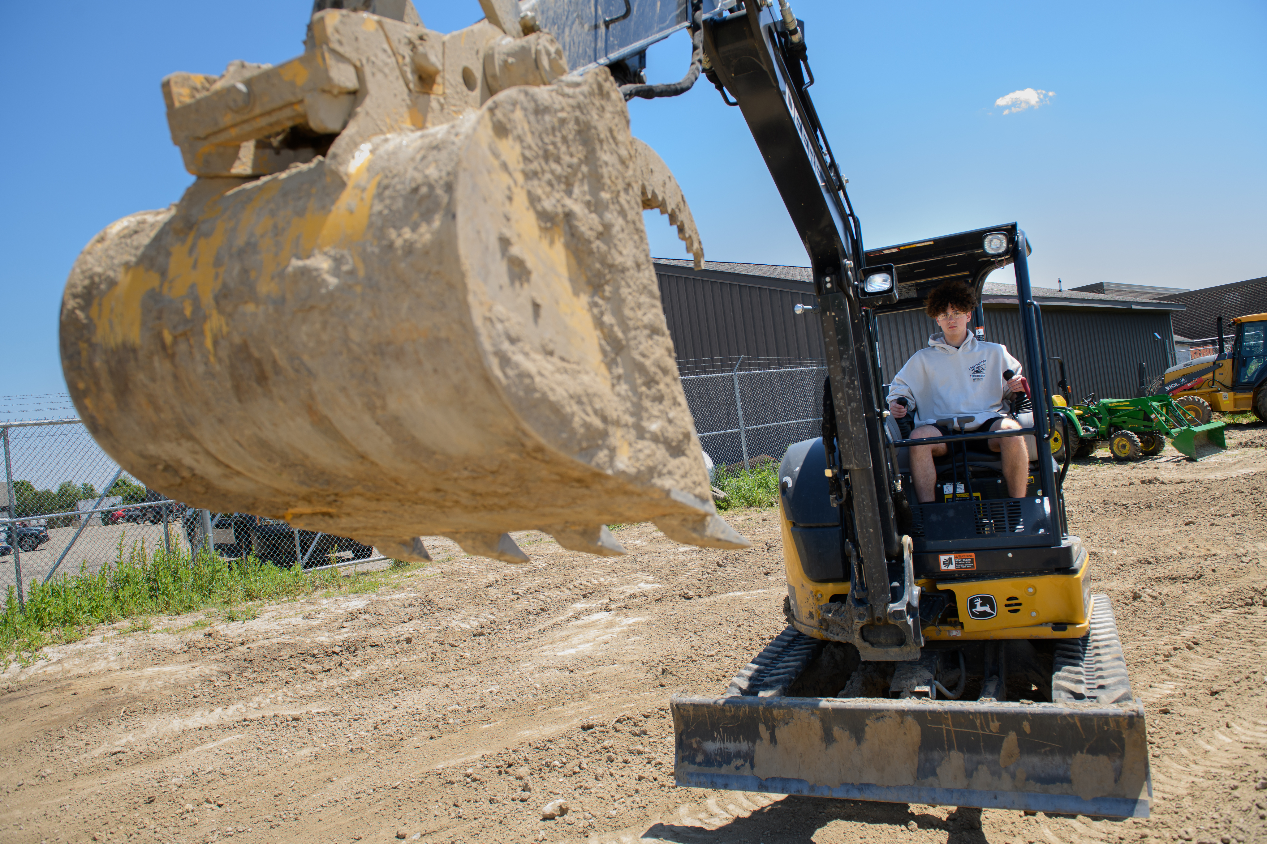 Male construction student sitting in the bulldozer ready to dig up some dirt.