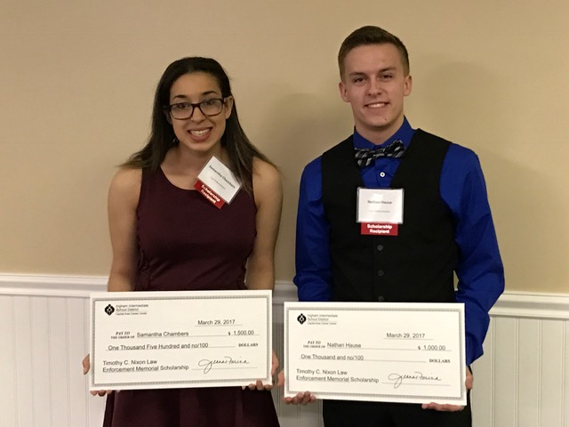 A female and male student show off their scholarship checks from the Tim Nixon Memorial Fund